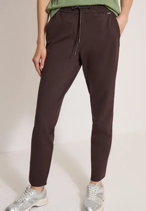 Pantalon marron foncé pour femme avec taille élastique et cordon, porté avec des baskets.
