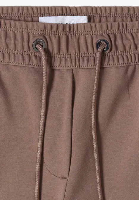 Gros plan d’un pantalon marron à taille élastique et cordon de serrage.