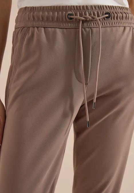 Gros plan sur un pantalon de jogging marron clair, taille élastique et cordon, vue latérale