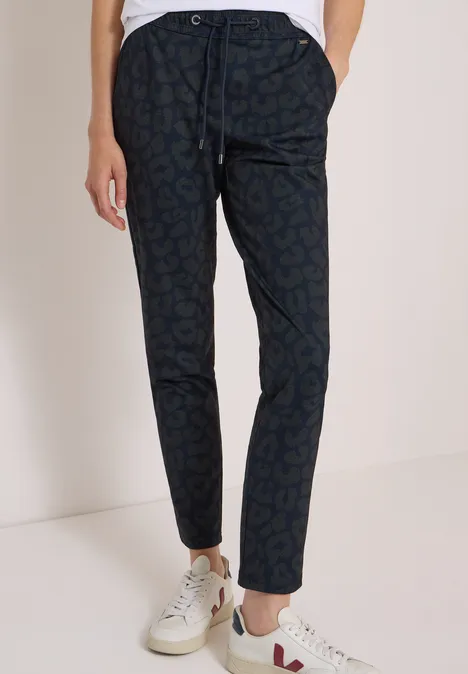 Mid Waist Slim Leg Hose im Casual Fit dark navy blue Schmale dunkelblaue Hose mit dezentem Muster, Tunnelzugbund und weißen Sneakern.