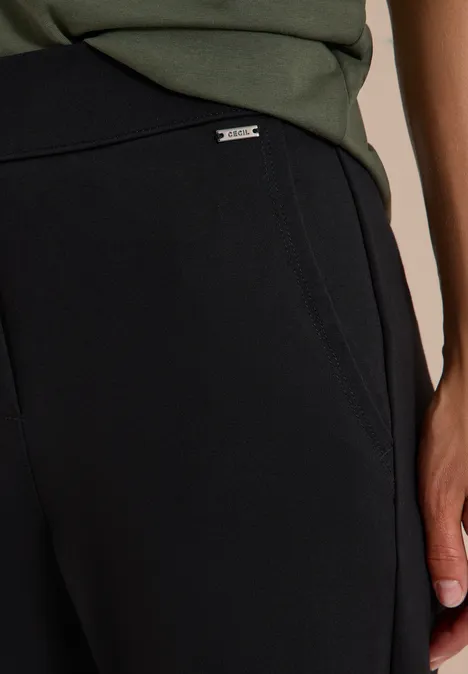 Schwarze, weiche Hose mit seitlichen Eingrifftaschen und kleinem Metall-Label am Taillenbund.