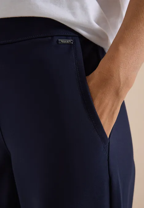 Nahaufnahme einer Person, Hand in dunkelblauer Hose mit kleinem Markenlabel.