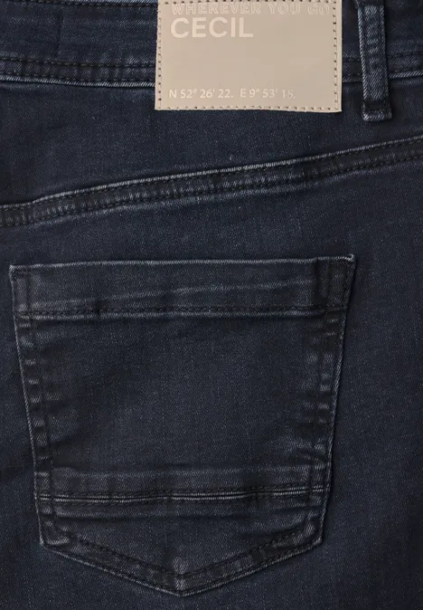 Gros plan d'un jean bleu foncé, poche arrière et étiquette de marque 'Cecil'.