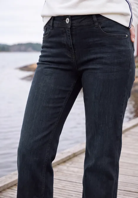 Jean foncé porté sur un pont en bois au bord de l'eau, vue de face jusqu'à la taille.