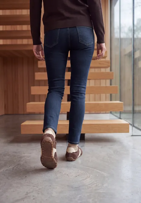High Waist Skinny Leg Jeggings im Slim Fit rinsed wash Eine Person in Jeans und braunen Schuhen steigt eine moderne Treppe hinauf.