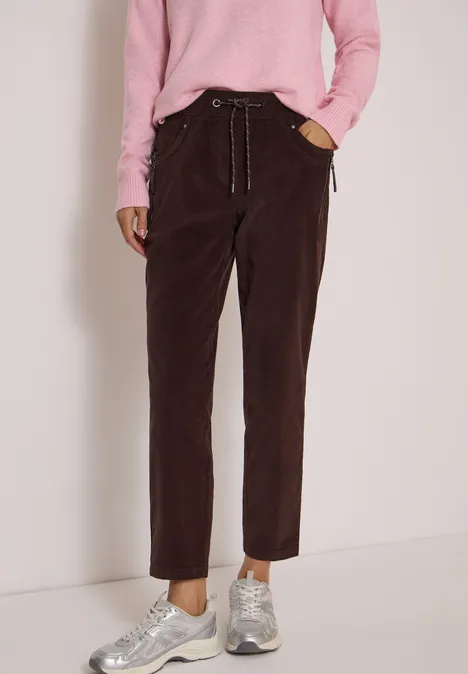 Mid Waist Slim Leg Hose im Casual Fit truffle brown Braune Cordhose mit seitlichen Taschen, locker geschnitten, kombiniert mit rosa Pullover und grauen Sneakern.