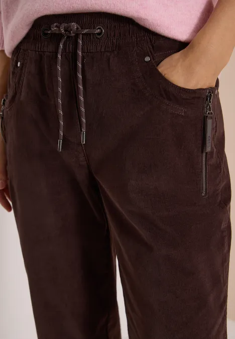 Mid Waist Slim Leg Hose im Casual Fit truffle brown Nahaufnahme einer braunen Cordhose mit elastischem Bund, Kordelzug und Reißverschlusstaschen.