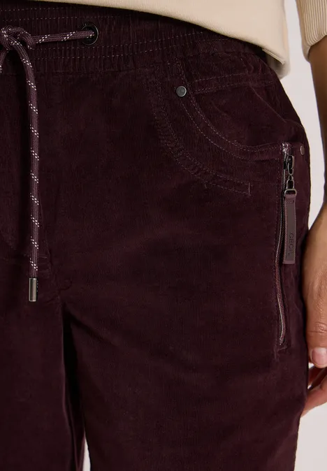 Mid Waist Slim Leg Hose im Casual Fit berry red Nahaufnahme einer bordeauxfarbenen Cordhose mit Tunnelzugbund und seitlicher Reißverschlusstasche.