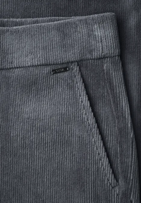 Detailaufnahme einer grauen Cordhose mit Taillenbund und schräger Eingriffstasche.