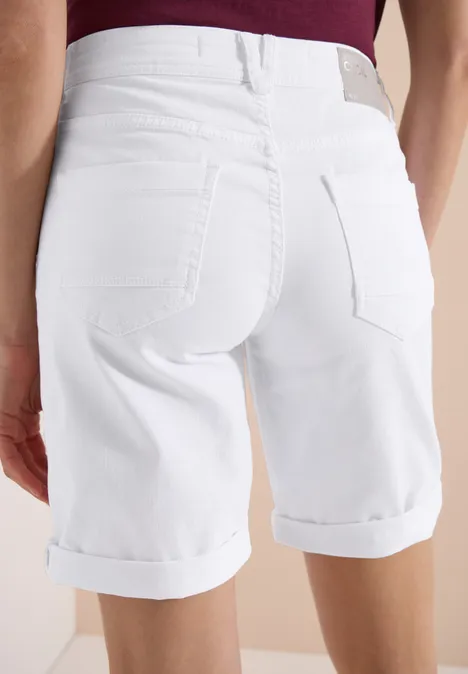 Hinteransicht einer Person in weißen, hochgekrempelten Bermudashorts und dunkelrotem Oberteil.