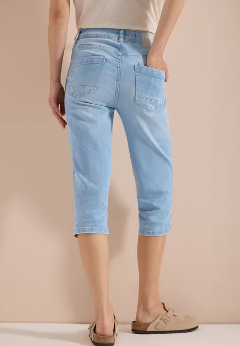 High Waist Slim Leg Jeans im Slim Fit light blue random bleached Rückansicht einer Person in hellblauen 3/4-Jeans und beigen Loafers vor neutralem Hintergrund.