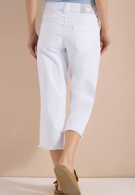 Rückansicht: weisse, knöchellange Jeans mit weitem Bein und beigen Sandaletten.