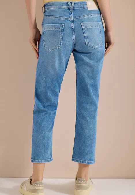 Vrouw van achter in lichtblauwe jeans en beige sneakers