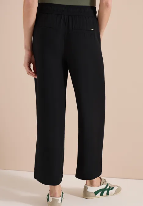 Schwarze, locker sitzende Hose mit hohem Bund, seitlichen Taschen und halblangem Bein.