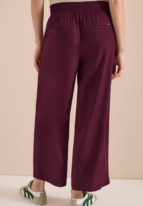 Rückansicht einer Person, die eine weite, lila Hose mit elastischem Bund trägt.