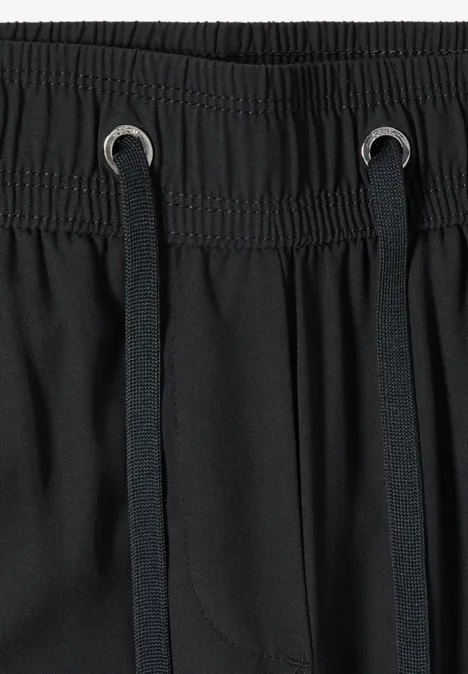 Gros plan sur une taille de pantalon noir élastique, cordons noirs et œillets métalliques.