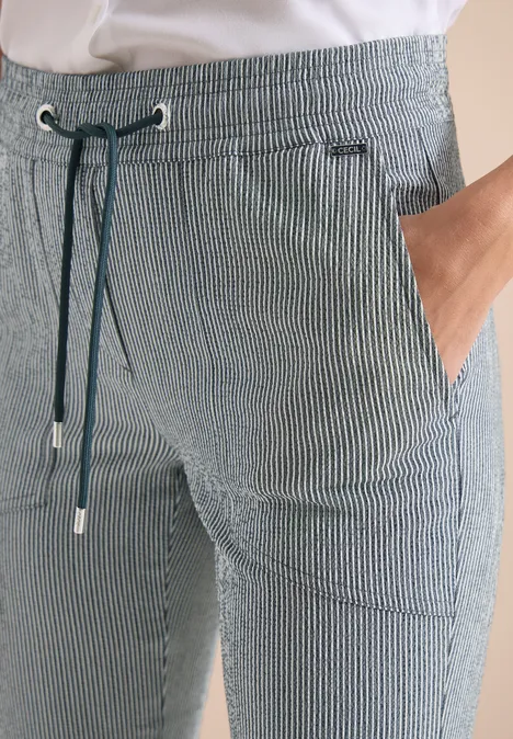Close-up van een grijze, gestreepte broek met tunnelsluiting en zijzakken.