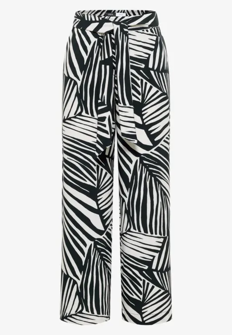 Schwarz-weiße, weit geschnittene Hose mit Blattmuster und passendem Gürtel.