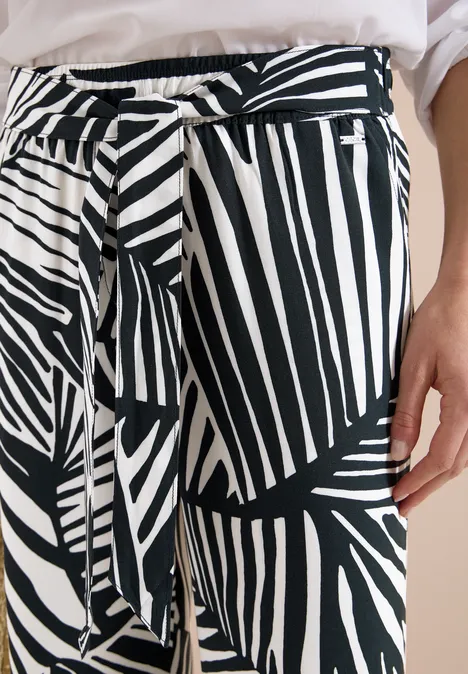 Nahaufnahme einer schwarz-weißen Hose mit variierenden Streifen und gebundenem Taillengürtel.