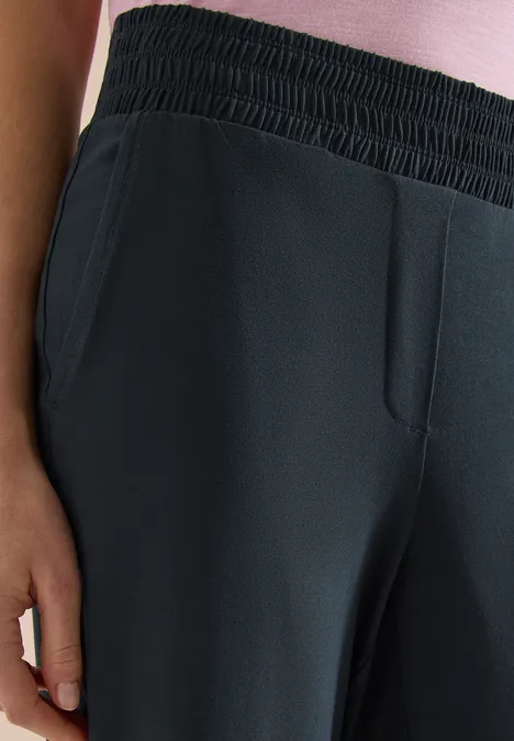 Donkere broek met elastische taille, schuine steekzakken, voornaad en een ontspannen pasvorm.