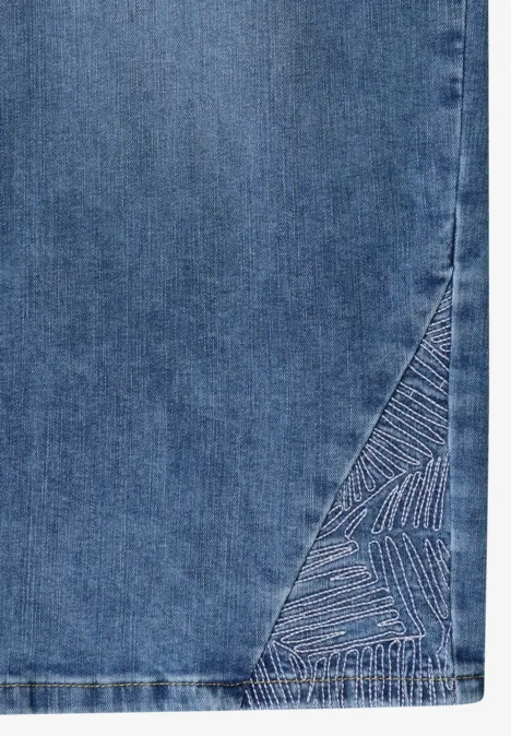 Ein Teil eines blauen Denimrocks mit gesticktem, dreieckigem Muster am Saum.