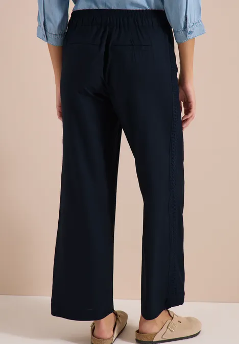 Wide Leg Hose mit tonalem Tape-Detail universal blue Rückansicht einer Person mit weiten schwarzen Hosen und elastischem Bund.