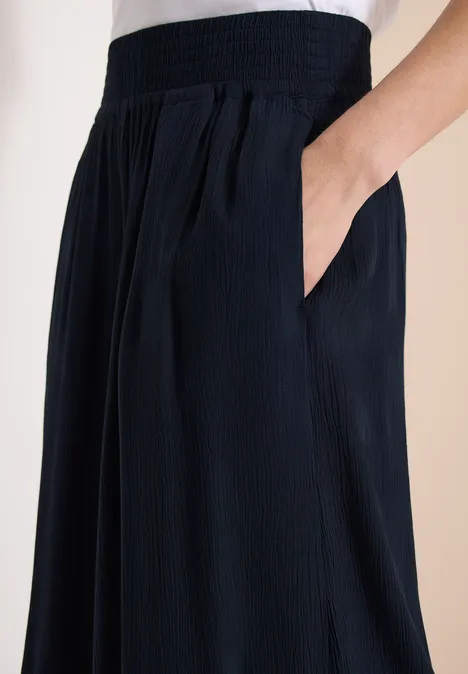 Pantalon large bleu foncé à taille élastique, poches latérales et plis légers.