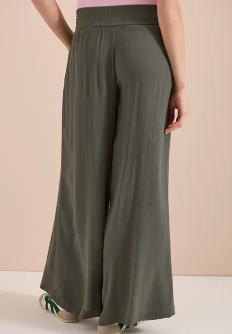 Vue de dos d'une personne portant un pantalon fluide taille haute couleur kaki.