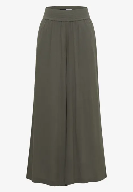 Pantalon ample à jambes larges en tissu fluide vert foncé avec taille haute élastique.