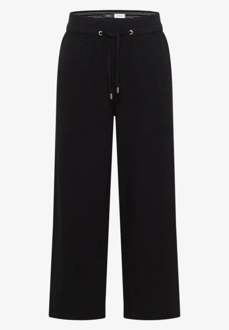 Schwarze, weite Stoffhose mit hohem Bund und Kordelzug.
