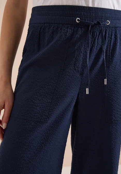 Nahaufnahme einer dunkelblauen, strukturierten Hose mit elastischem Bund und Kordelzug.