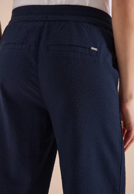 Rückansicht einer dunkelblauen, strukturierten Hose mit Gesäßtaschen und Taillenbund.