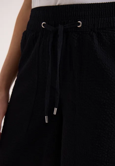Schwarze, strukturierte Hose mit Kordelzugbund und Seitentaschen.