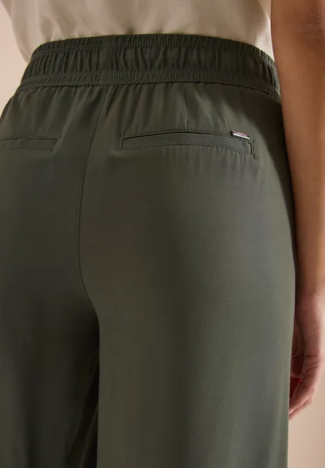 Nahaufnahme einer Person von hinten, trägt olivgrüne Hose mit elastischem Bund und Gesäßtaschen.