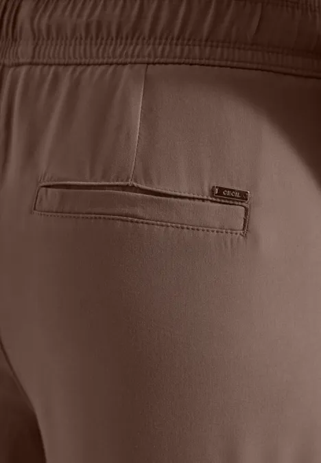 Nahaufnahme der Rückseite einer braunen Hose mit elastischem Bund und eingearbeiteter Tasche mit Reißverschluss.
