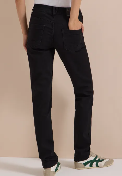 Schwarze Jeans mit geradem Schnitt, kombiniert mit weißen Sneakern und grünen Details