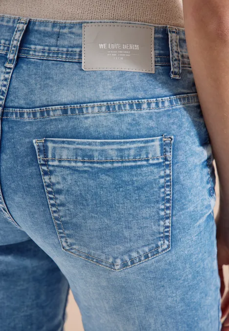 Ansicht einer Person von hinten in blauen Jeans mit Label 'WE CARE LABEL' am Bund.
