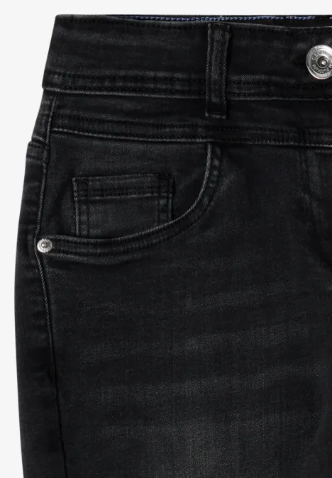 Close-up van zwarte jeans met voorzak, riemlussen en zilverkleurige knoop.