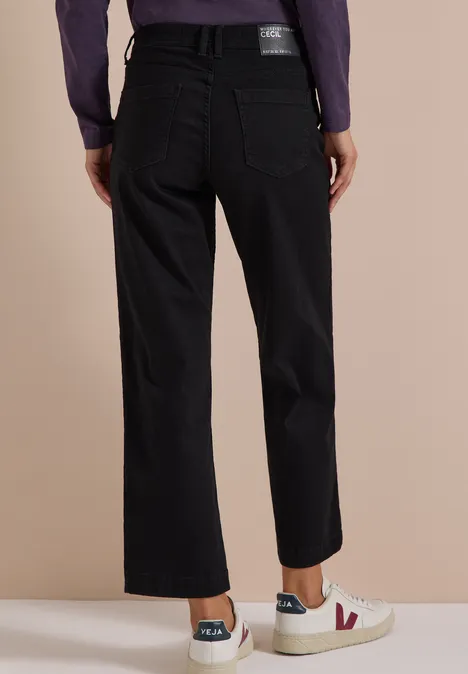 Schwarze Straight-Leg-Jeans mit großen Gesäßtaschen und weißen Sneakern, Rückansicht.