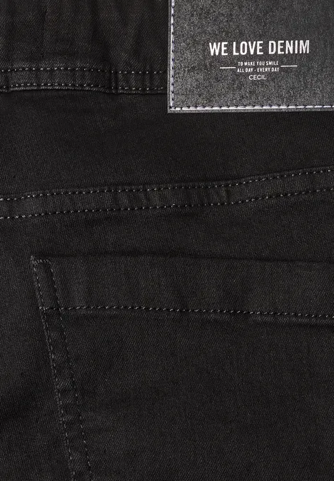 Nahaufnahme einer schwarzen Denim-Jeans mit Etikett 'WE LOVE DENIM' und sichtbaren Nähten