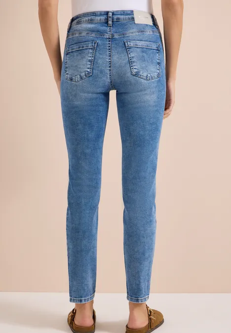High Waist Slim Leg Jeans im Slim Fit light blue used wash Rückansicht einer Person in hautengen blauen Jeans und Sandalen vor beigem Hintergrund.