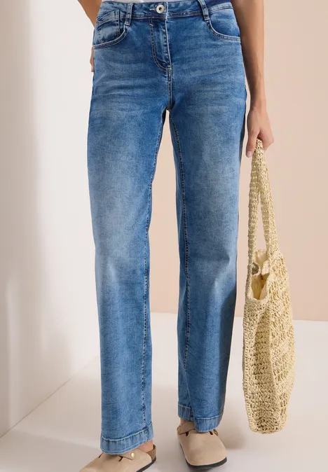High Waist Wide Leg Jeans im Loose Fit light blue used wash Person trägt hochgeschnittene, gerade geschnittene blaue Jeans, beige Ballerinas und hält eine Strohtasche.