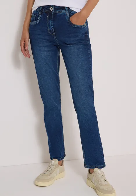 Jeans met High Waist en smalle pijpen in Slim Fit mid blue wash Blaue Straight-Fit-Jeans mit mittlerer Taille und Sneakers, Hand in Tasche.