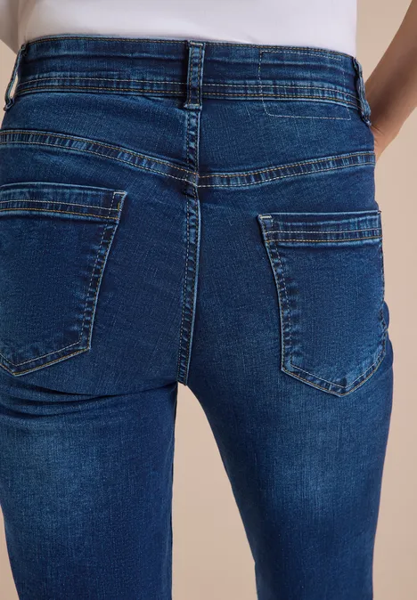 Jeans met High Waist en smalle pijpen in Slim Fit mid blue wash Nahaufnahme einer Person in eng anliegenden blauen Jeans von hinten.