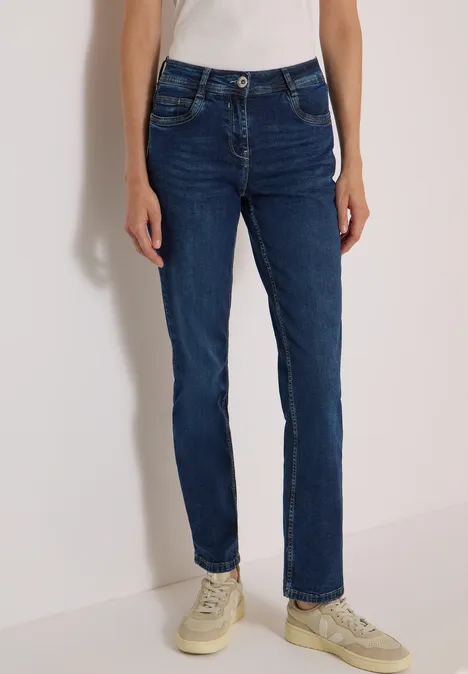 High Waist Straight Leg Jeans w kroju Slim Fit Dark blue wash Osoba ma na sobie ciemnoniebieskie jeansy slim straight i beżowe trampki.