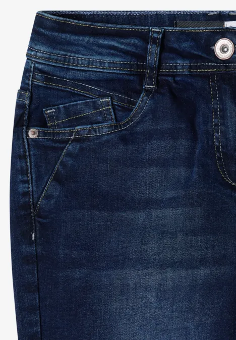 Mid Waist Slim Leg Jeans w stylu Casual Fit Dark blue wash Zbliżenie ciemnoniebieskich dżinsów z kieszeniami, pasem i guzikiem.