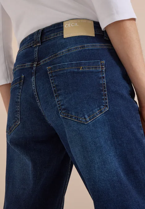High Waist Wide Leg Jeans w kroju Loose Fit Dark blue wash Zdjęcie od tyłu osoby w niebieskich dżinsach z dyskretną metką i białą bluzką.