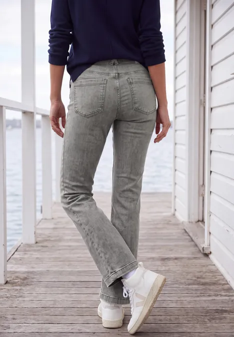 High Waist Bootcut Jeans im Slim Fit light grey wash Person im grauen Jeans, Rückenansicht, steht auf einem Steg am Wasser.