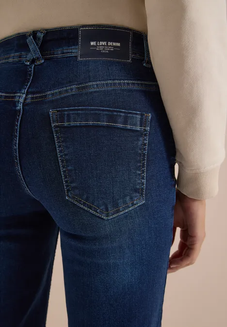 Achteraanzicht van een donkerblauwe spijkerbroek met zakken en merklabel in de taille, gedragen door een persoon.