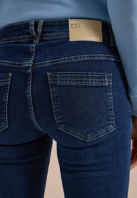 Achteraanzicht van een persoon in nauwsluitende blauwe jeans met opgestikte zakken en label op de taille.